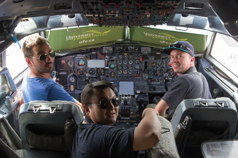 two men standing inside a cockpit on top of a plane