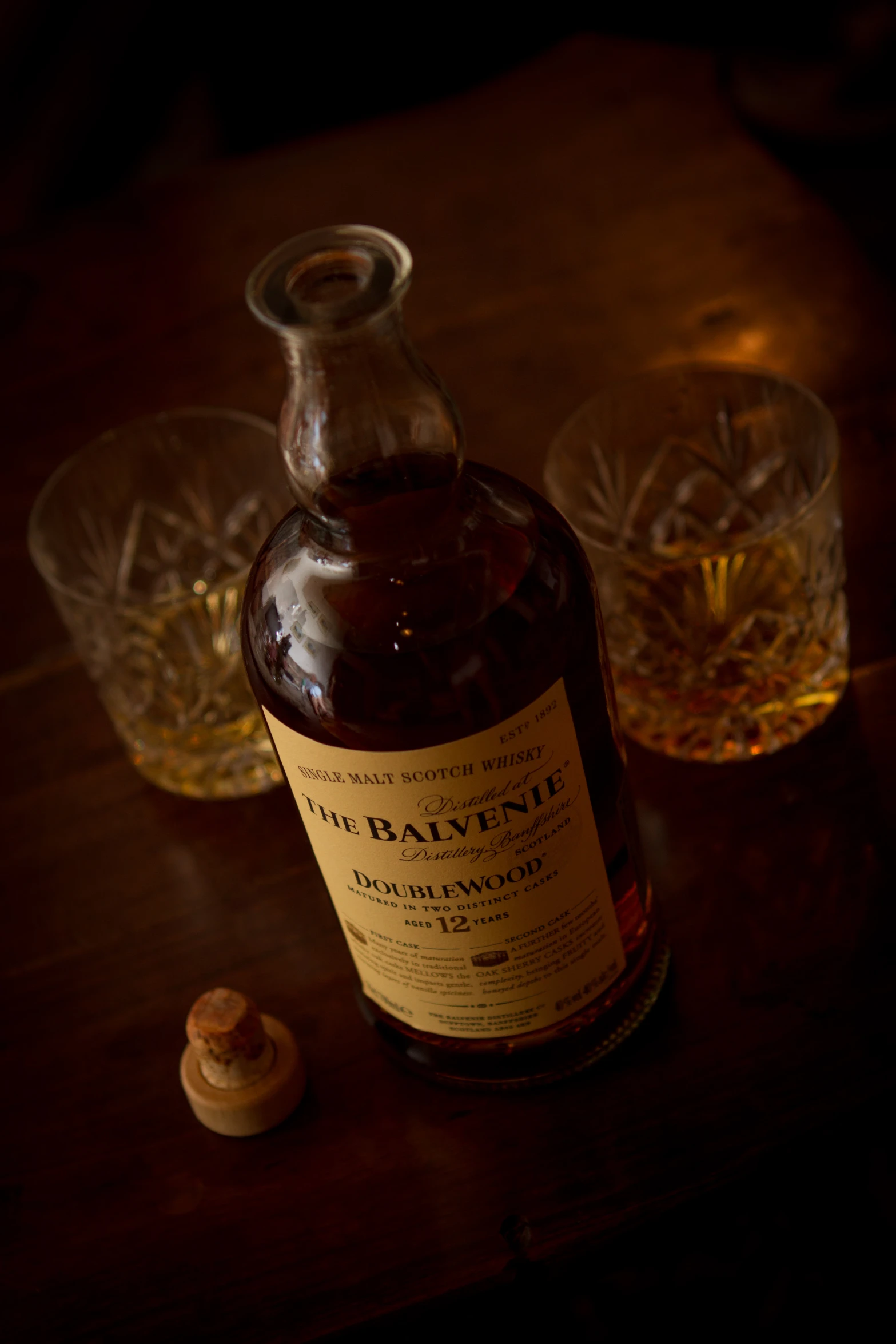 a bottle and two empty glasses sitting on a table