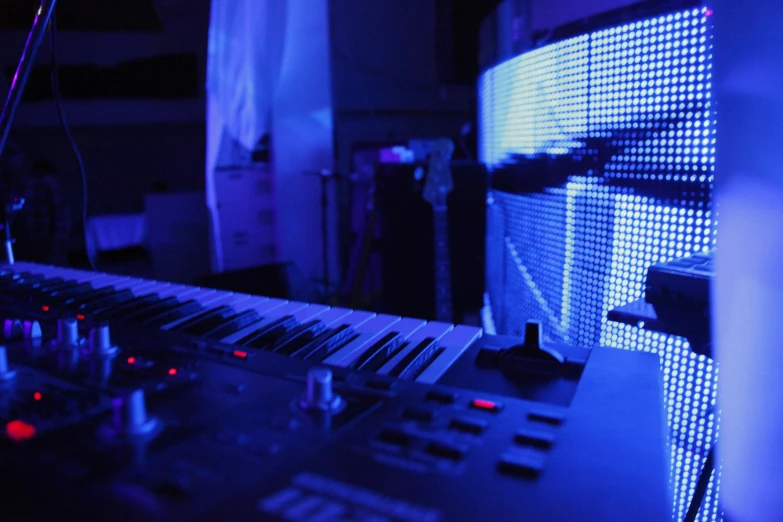 an electronic keyboard sitting in the dark with a blue light