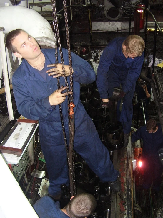 several men wearing blue work uniforms holding chains