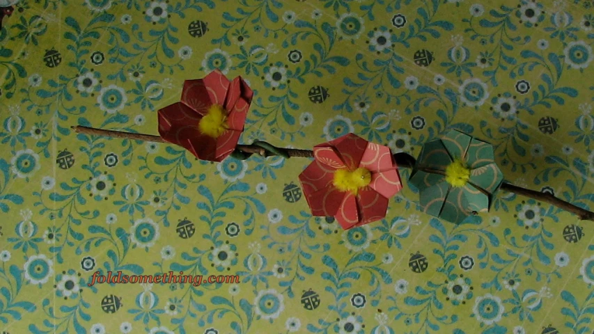 two folded paper flowers hang on the wall