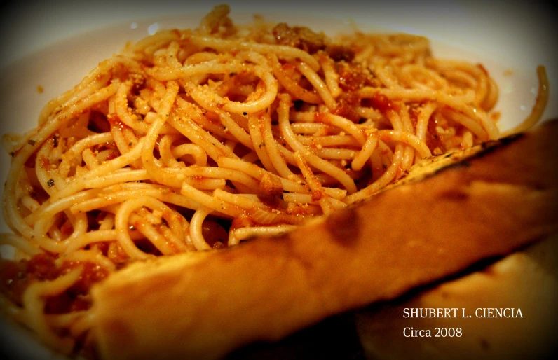 a pile of spaghetti sitting on a plate next to a sandwich