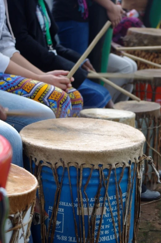 a group of drummers is sitting on the grass, with their drums resting on their backs