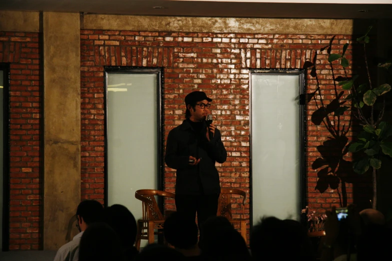 man with black glasses and a suit standing by glass doors