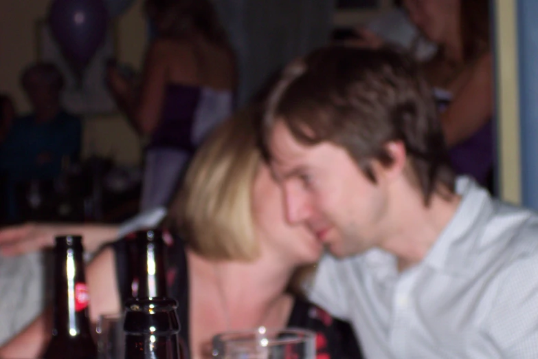 a man and a woman kissing in front of bottles
