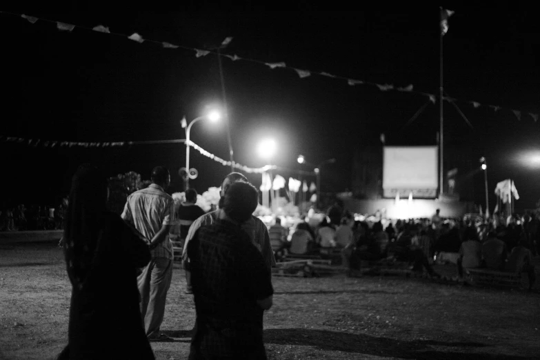 three people standing on the beach at night, one holding onto a stick