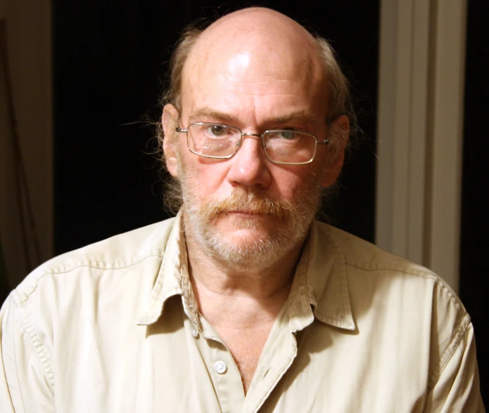 a man with a bald head in a cream shirt