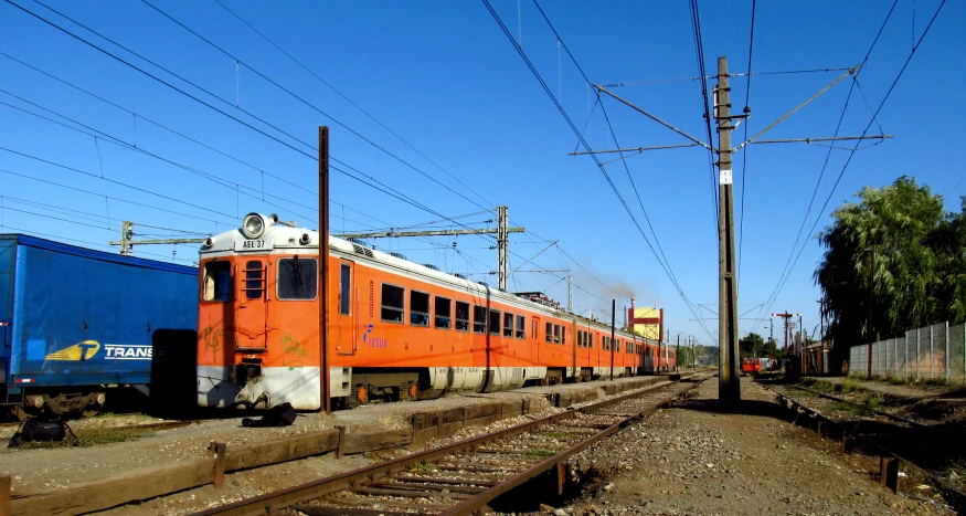 a long orange train is traveling down the tracks