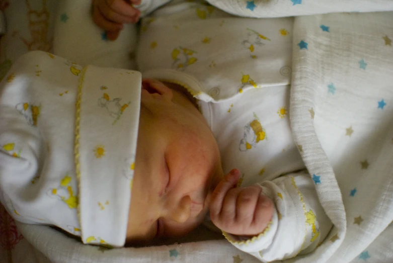 a small baby wearing a hat and lying on a blanket