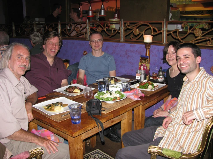 a group of men sit around a wooden table
