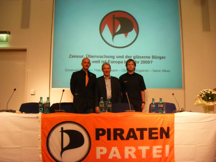 three men standing in front of a sign for pirates in berlin