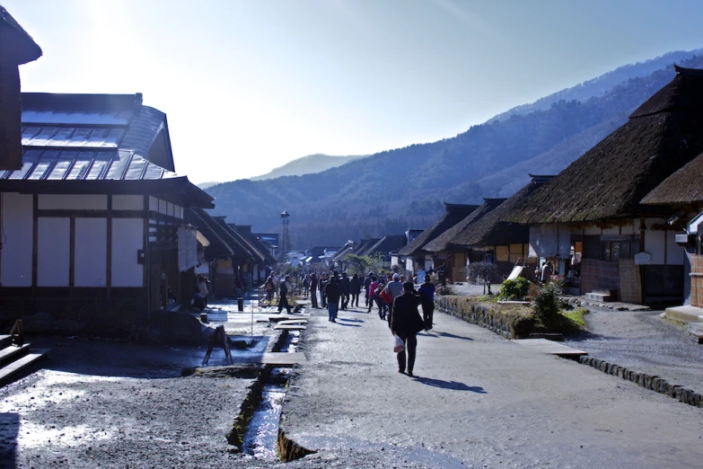 people walk through a village on a sunny day