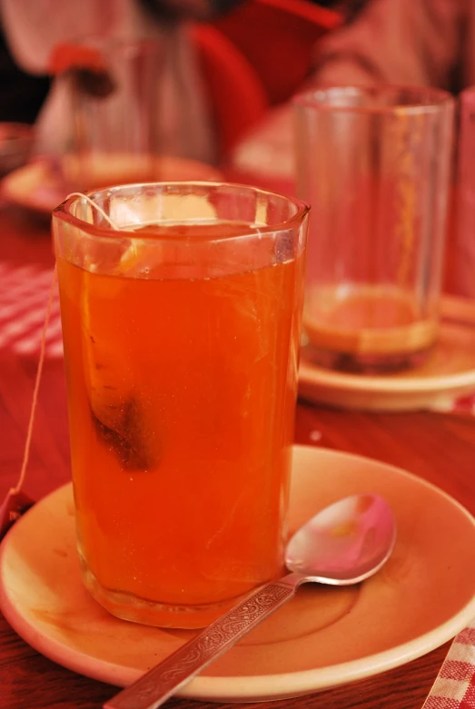 an orange cocktail sits in front of two empty glasses