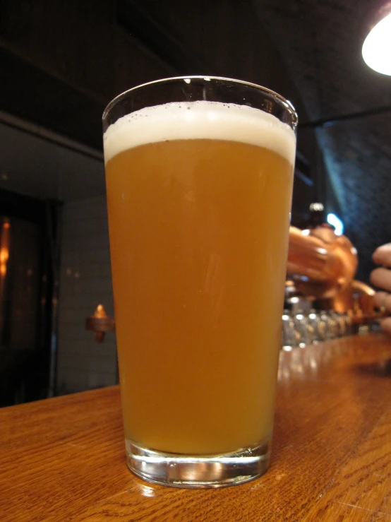 a glass on a table that has some beer in it