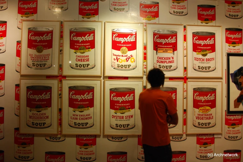 two people in front of a red and white wall with shelves with some items on it