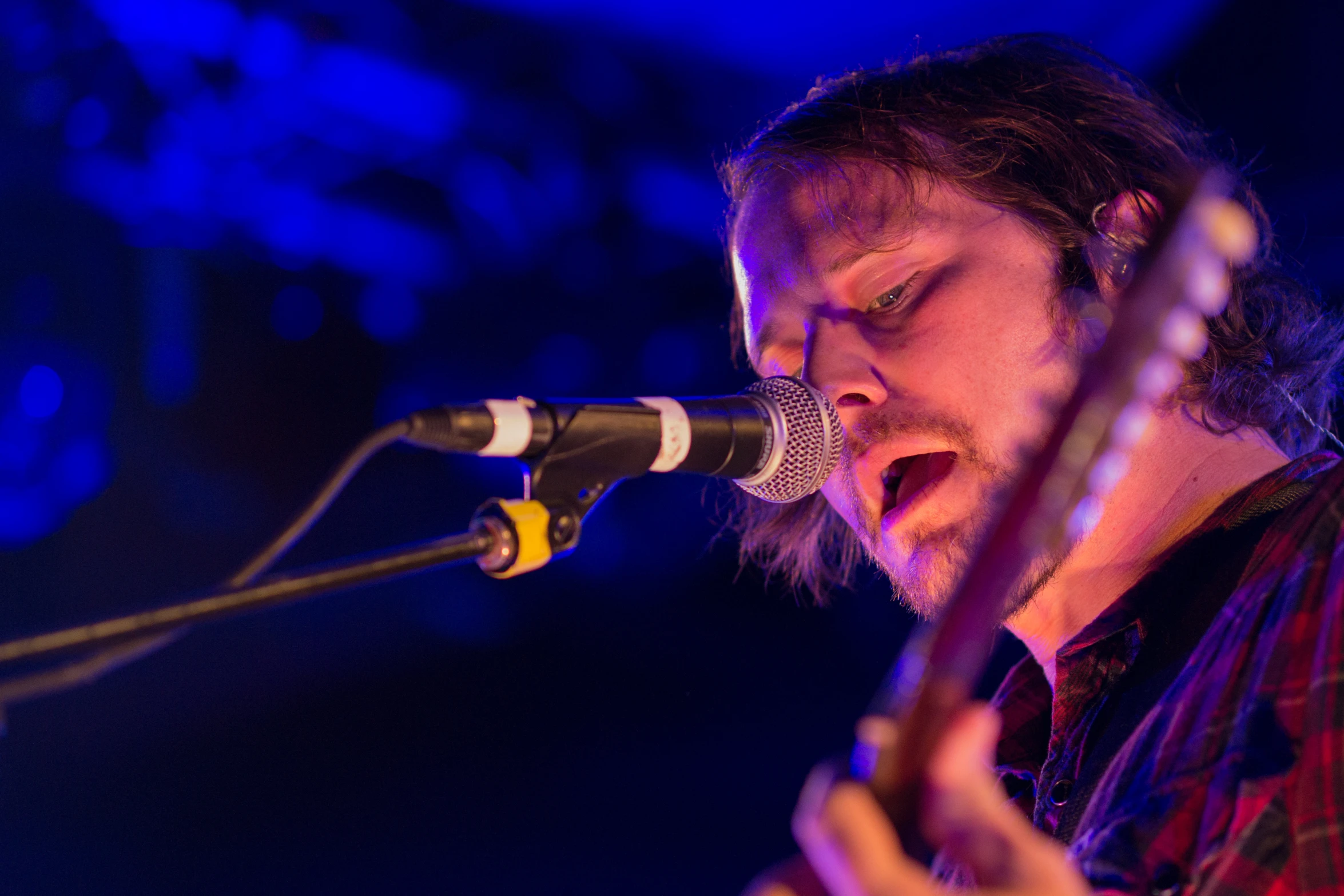 the singer is playing his guitar and singing into the microphone