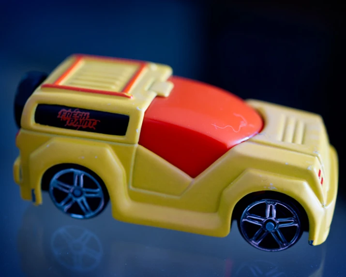 a plastic toy car with yellow wheels and red seat