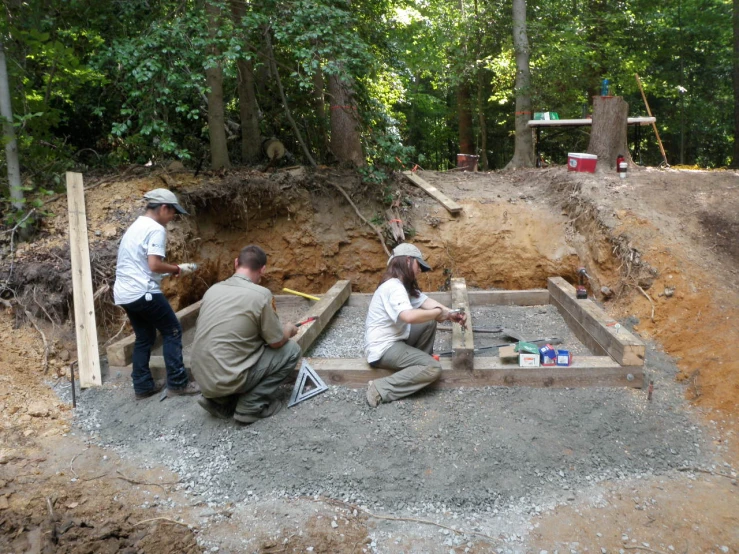 three people building a pit together in the woods