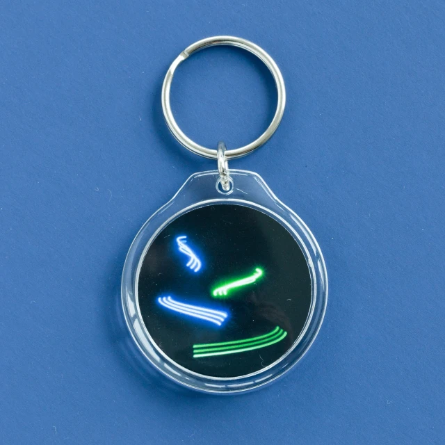 a green keychain with a face and a yellow, red and black smile