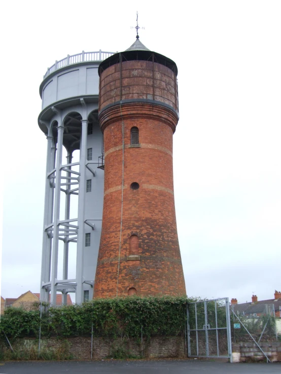 a large brick tower sitting next to a lush green hedge