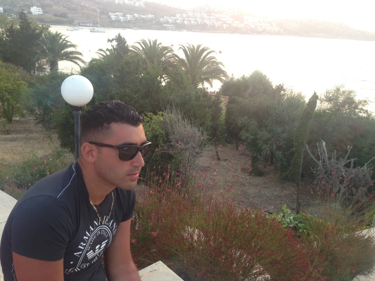 a man with sunglasses sitting on a ledge