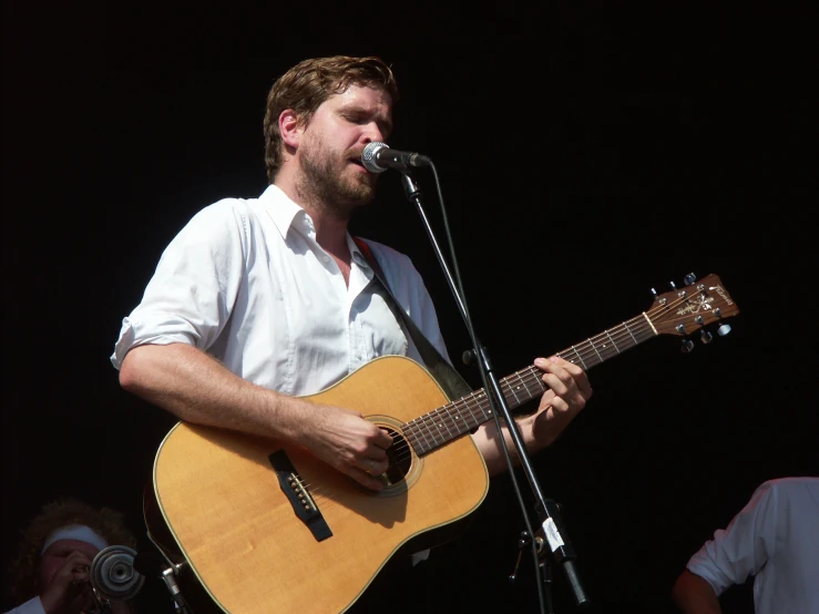 a man holding a guitar up in front of a microphone