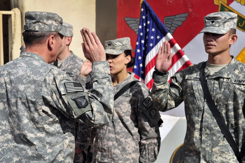 military men and women saluting for each other with flags behind them