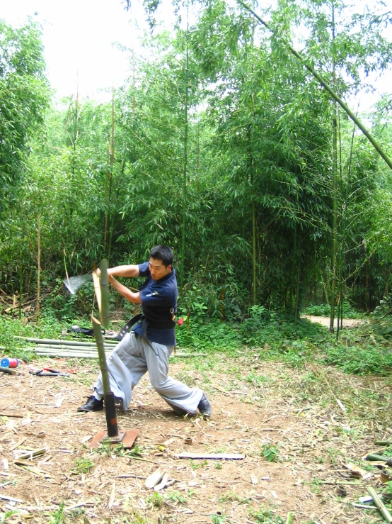 man playing baseball in the woods with trees behind him