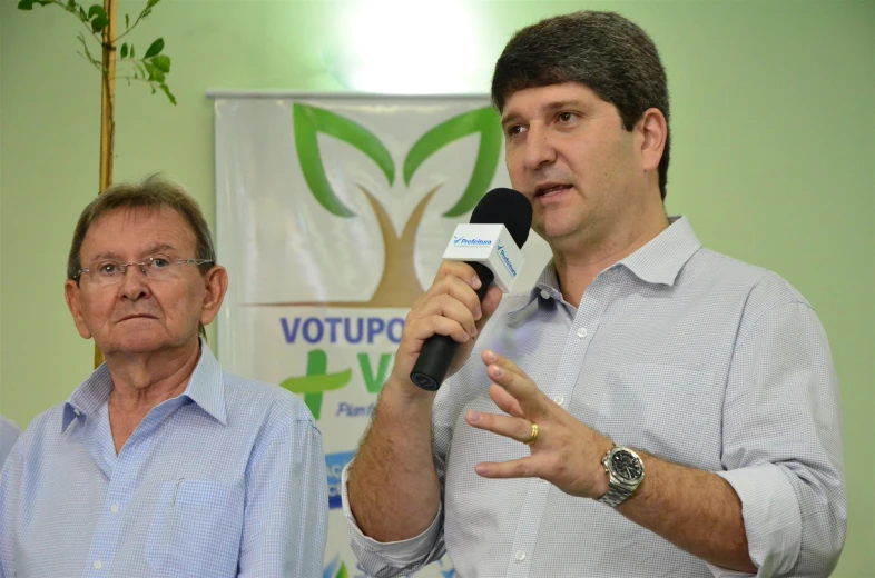 two men stand in front of a microphone speaking