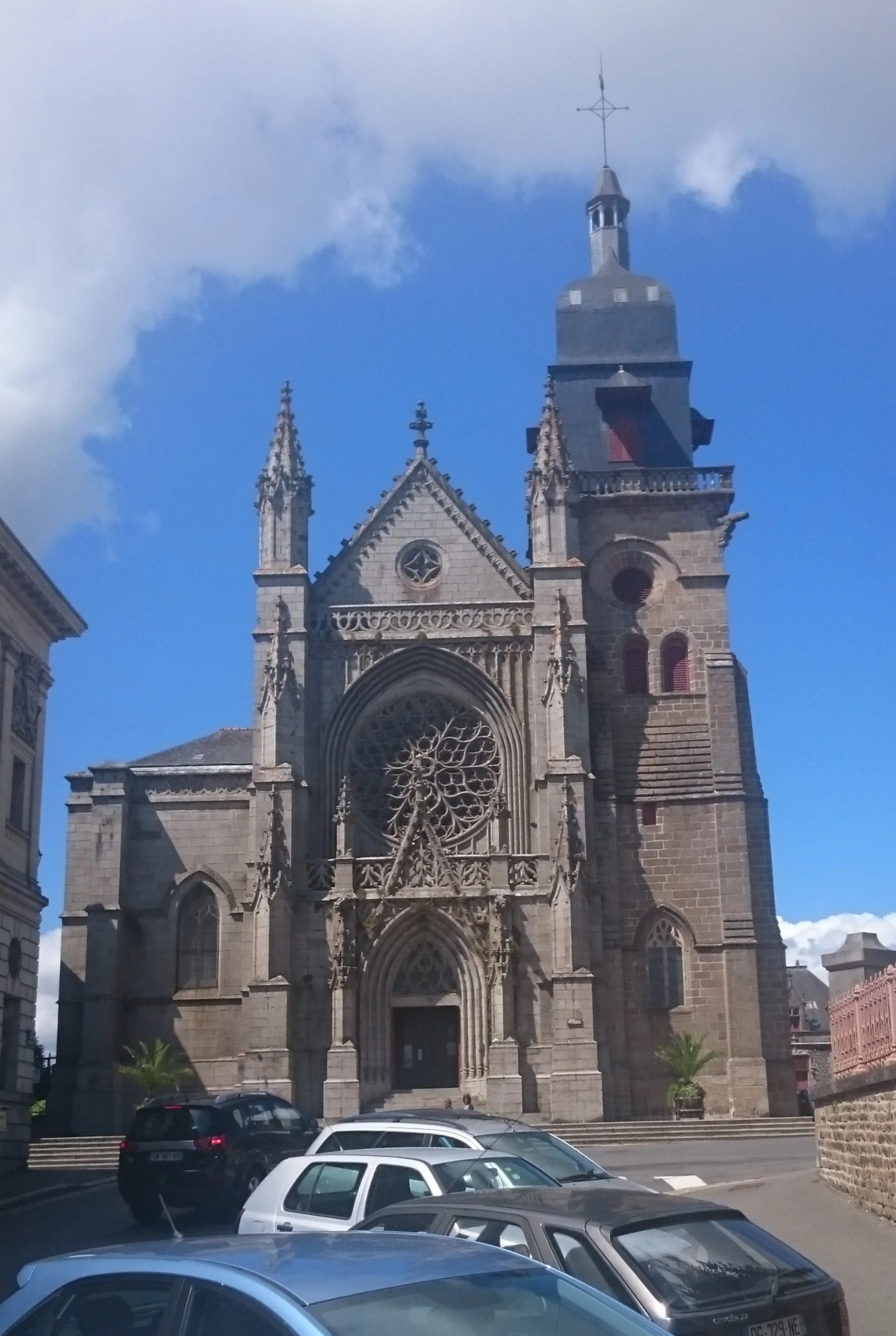 a group of cars parked in front of a tall cathedral