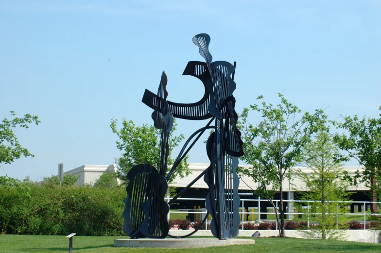 a tall metal sculpture in the grass next to trees