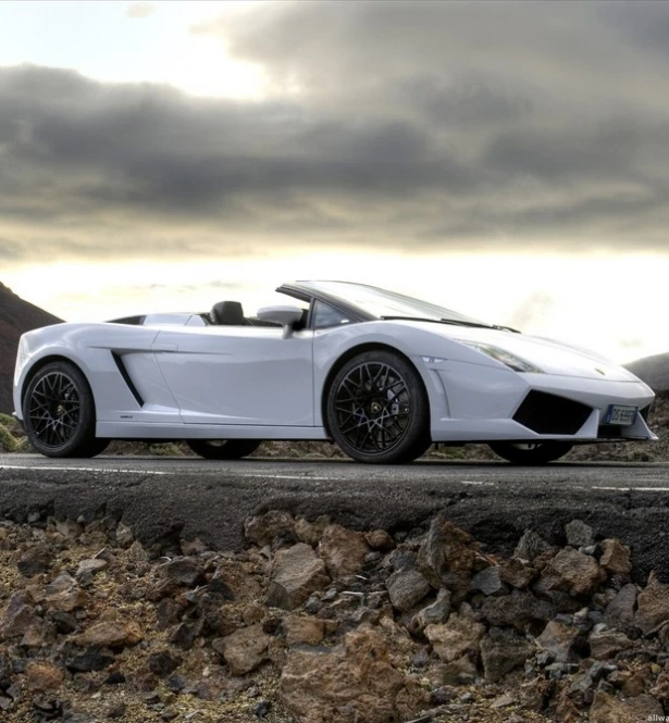 the front end of a white sports car driving on the road