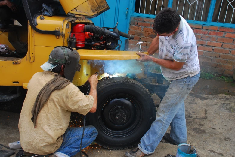 a couple of men are work on a piece of metal