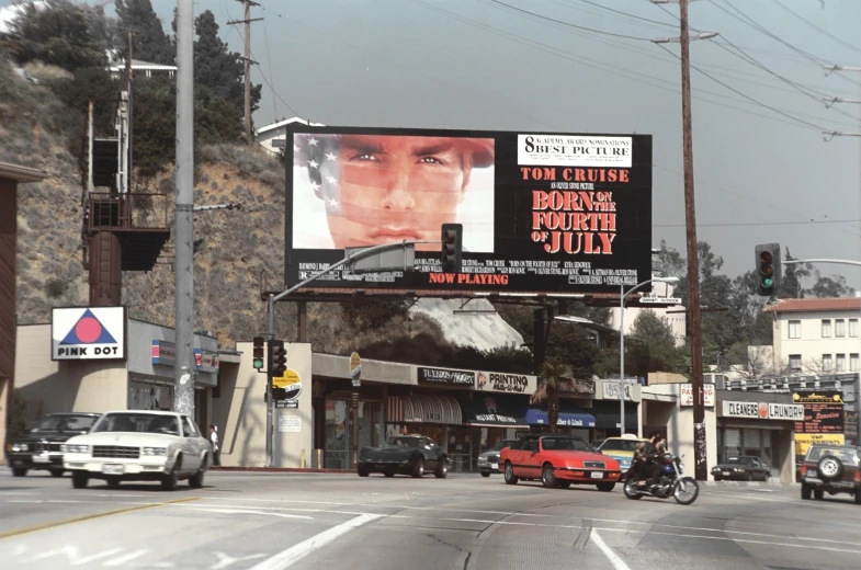 a movie billboard in a town near a hill
