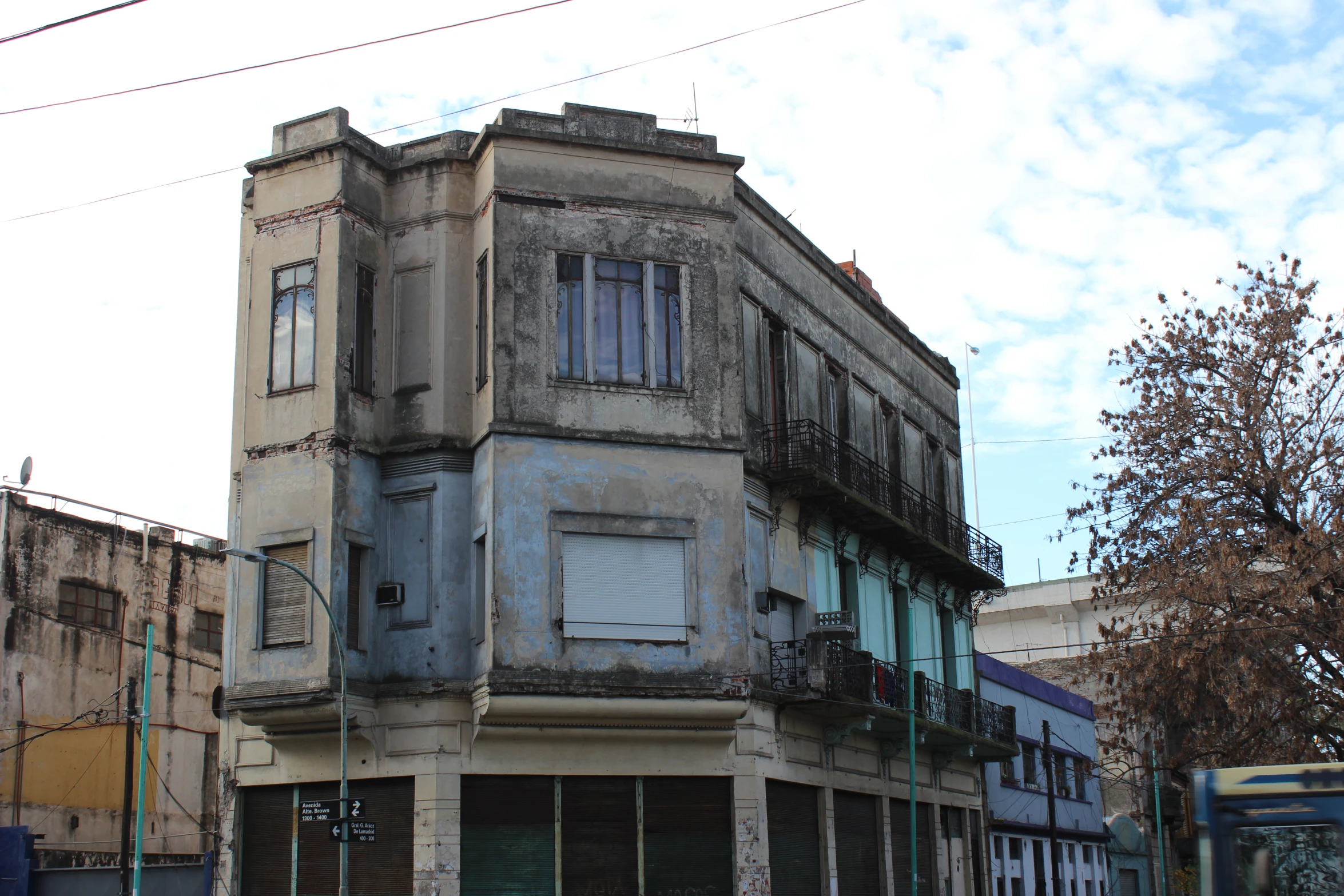 an old building has a broken shutter on the front and second story