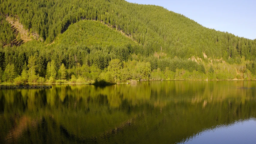 the view of a mountain range next to a lake with a canoe