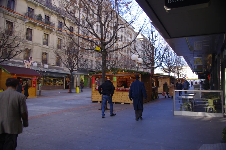 people walking through a sidewalk with a building in the background