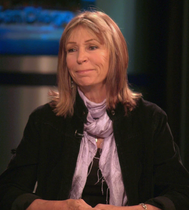 a woman sits next to a table wearing a purple scarf