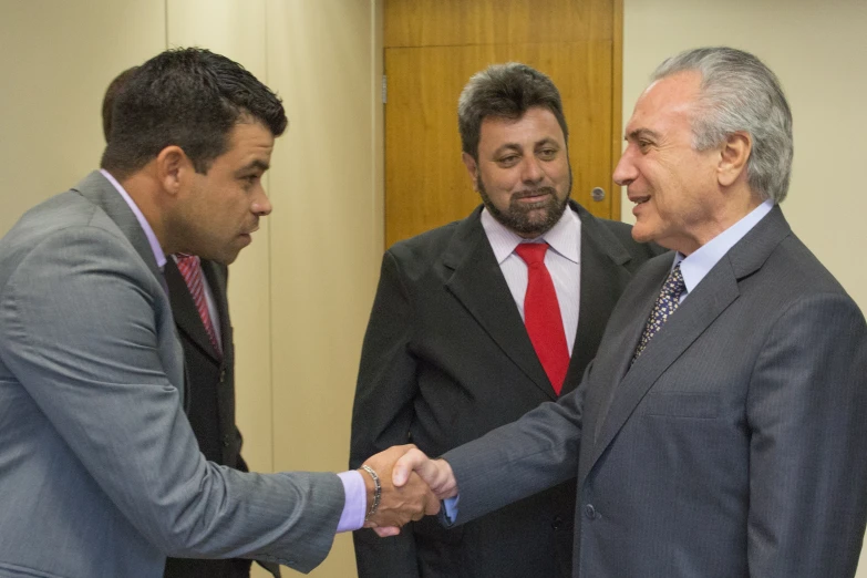 two men in suits shaking hands at the end of a meeting