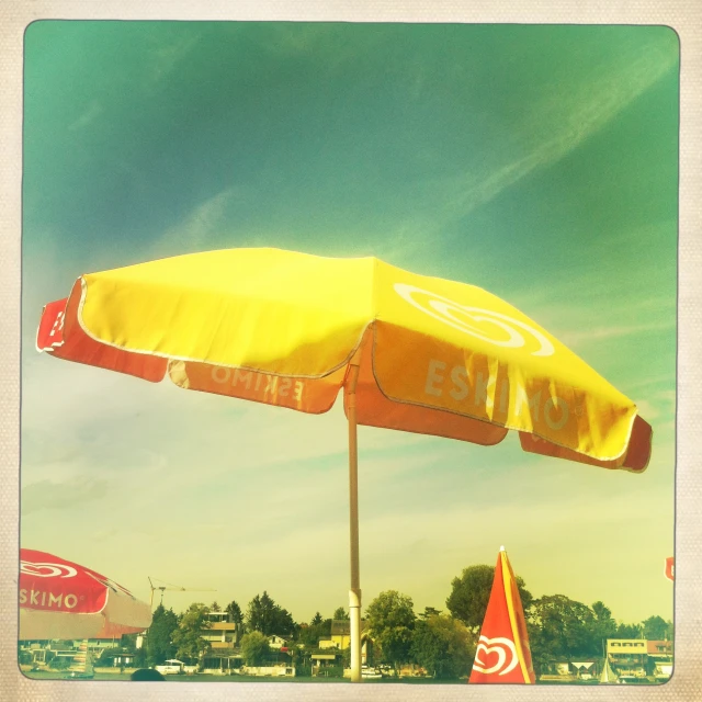 a yellow beach umbrella on top of a green lawn