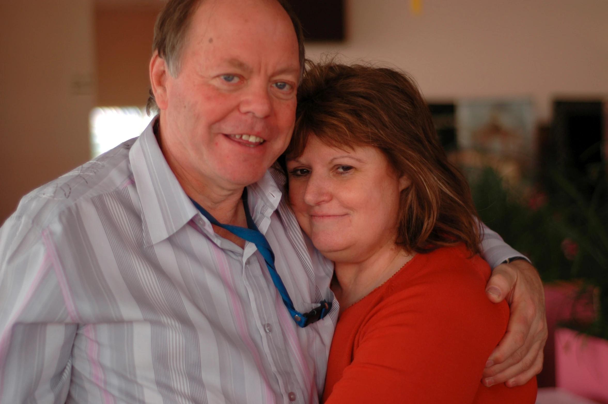 a man and a woman hug each other in a room