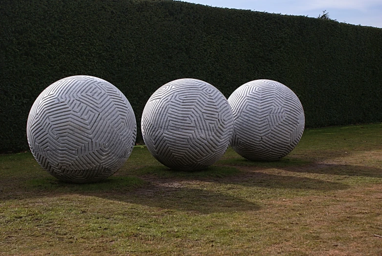 three large balls with designs are lined up in a field