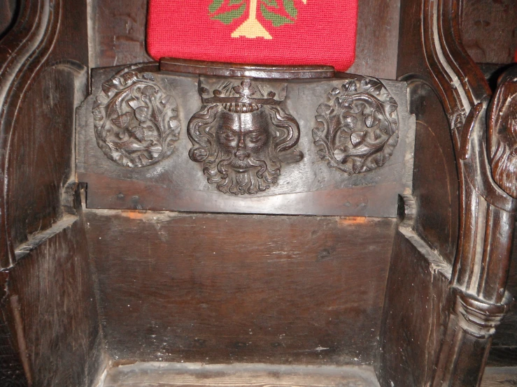 an old wooden throne with a red seat cushion