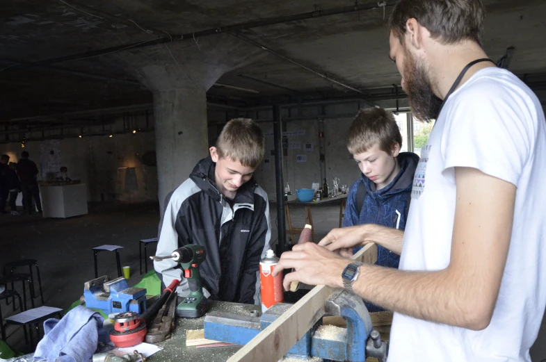 three boys in a garage looking at some items