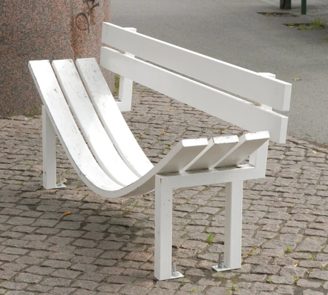 a white bench next to a brick road