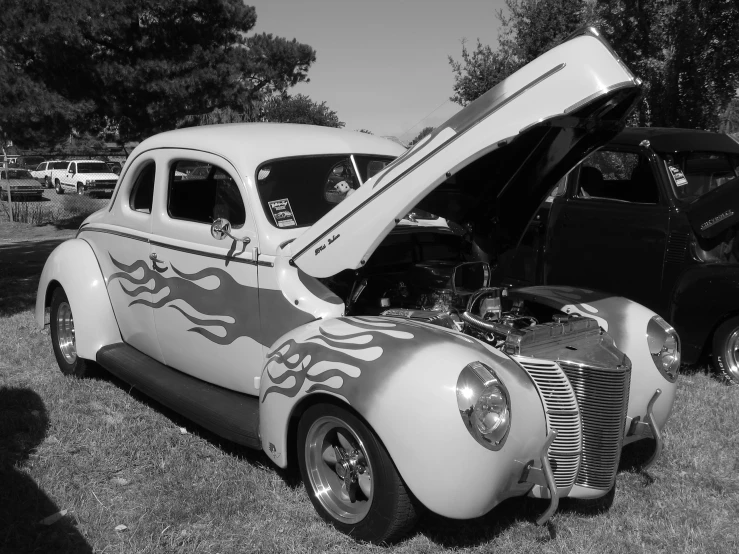 an old car with the hood up and flames on it