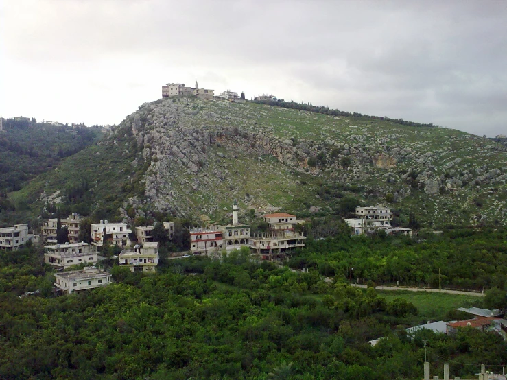 several buildings on a hill side near trees