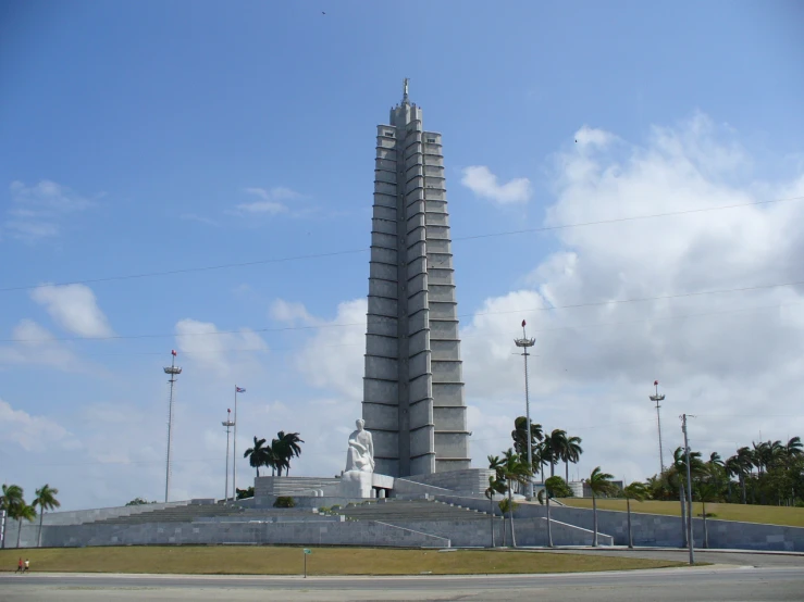 a statue stands with palm trees surrounding it