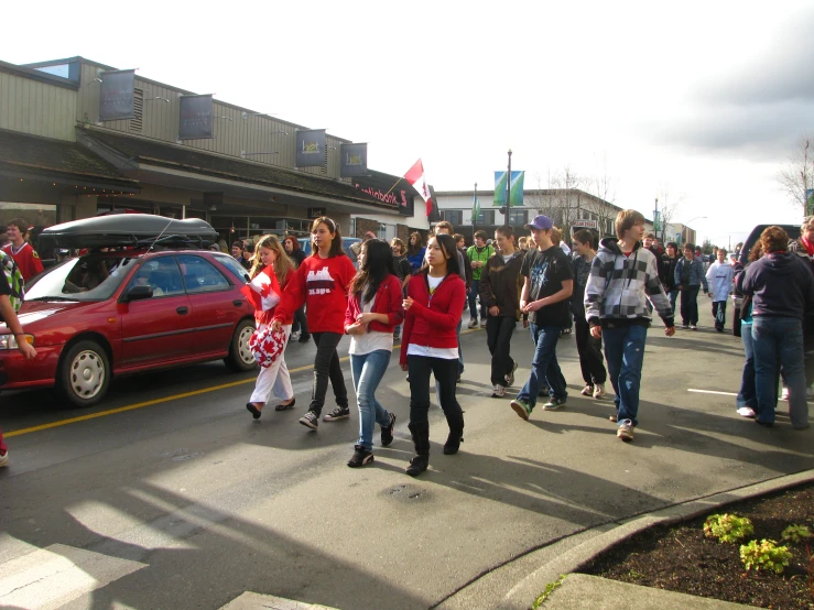 several people walking on the street next to cars