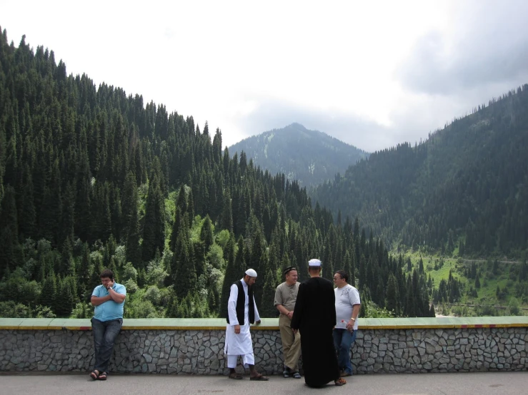 four people standing on a stone wall looking at mountains